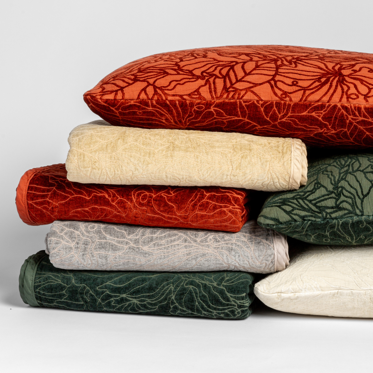 Georgia Throw Pillow | A cluster of three Georgia shams  displayed on their cotton jacquard side and four Georgia blankets displayed on their chenille jacquard sides, all against a white background