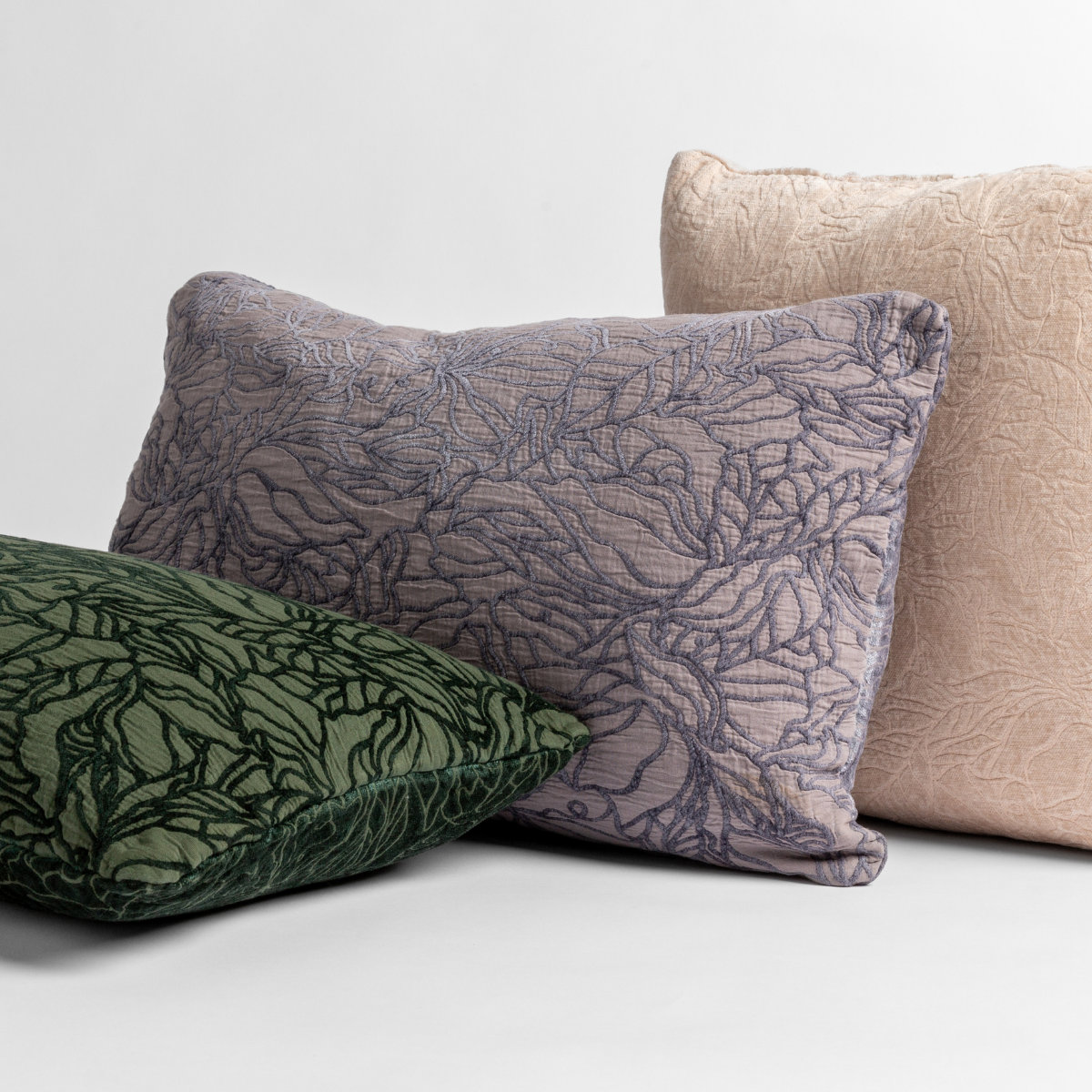 Georgia Throw Pillow | three throw pillows shown leaning against one another, in different colors with different sides showing their cotton jacquard and chenille jacquard faces - shown against a white background. 