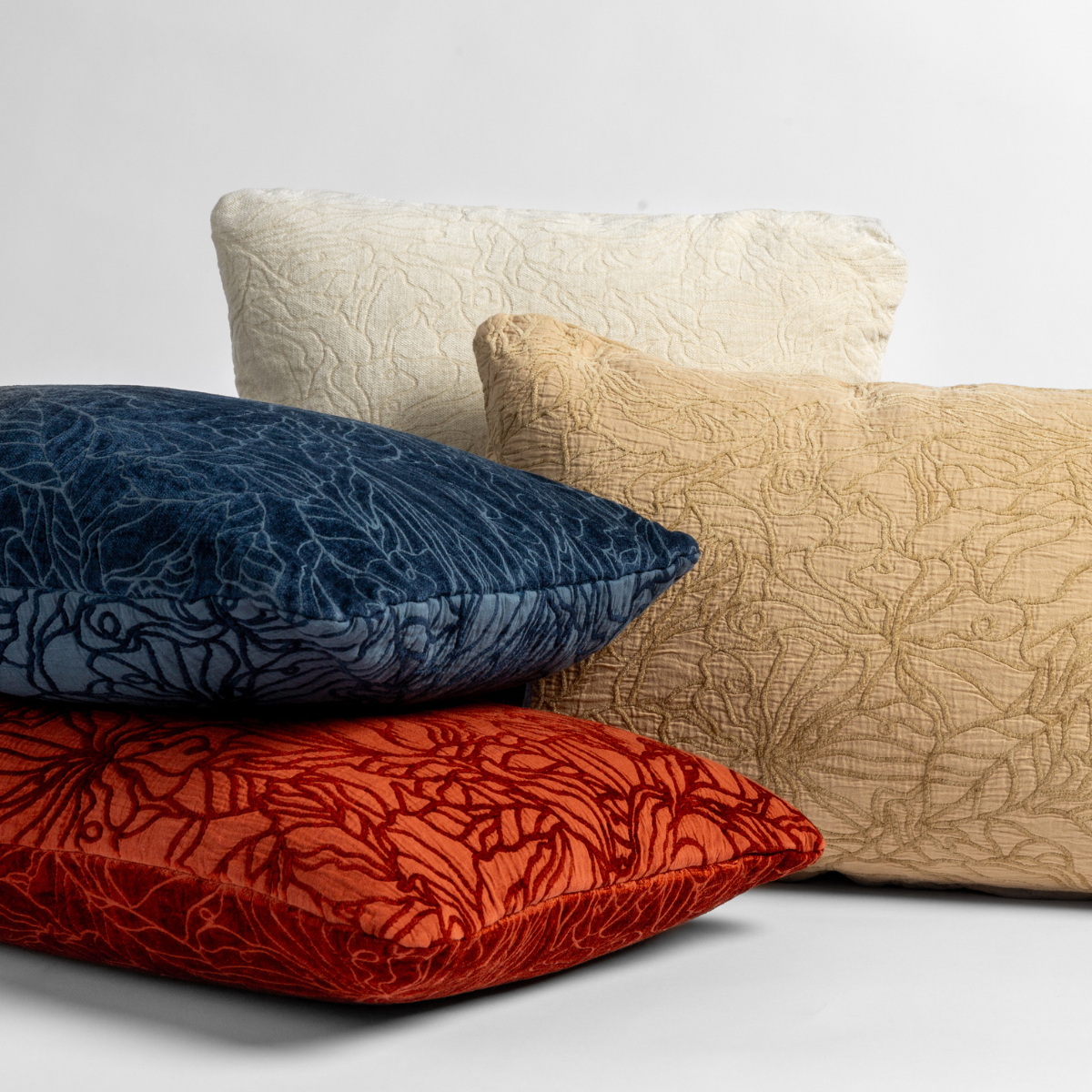 Four Georgia throw pillows shown in a fun array against a white background on either their chenille jacquard or cotton jacquard sides in the following colorways | Winter White, a wooly and warm tone, Honeycomb, a golden hue, Midnight, a rich indigo, and Autumn, a rich terracotta tone.