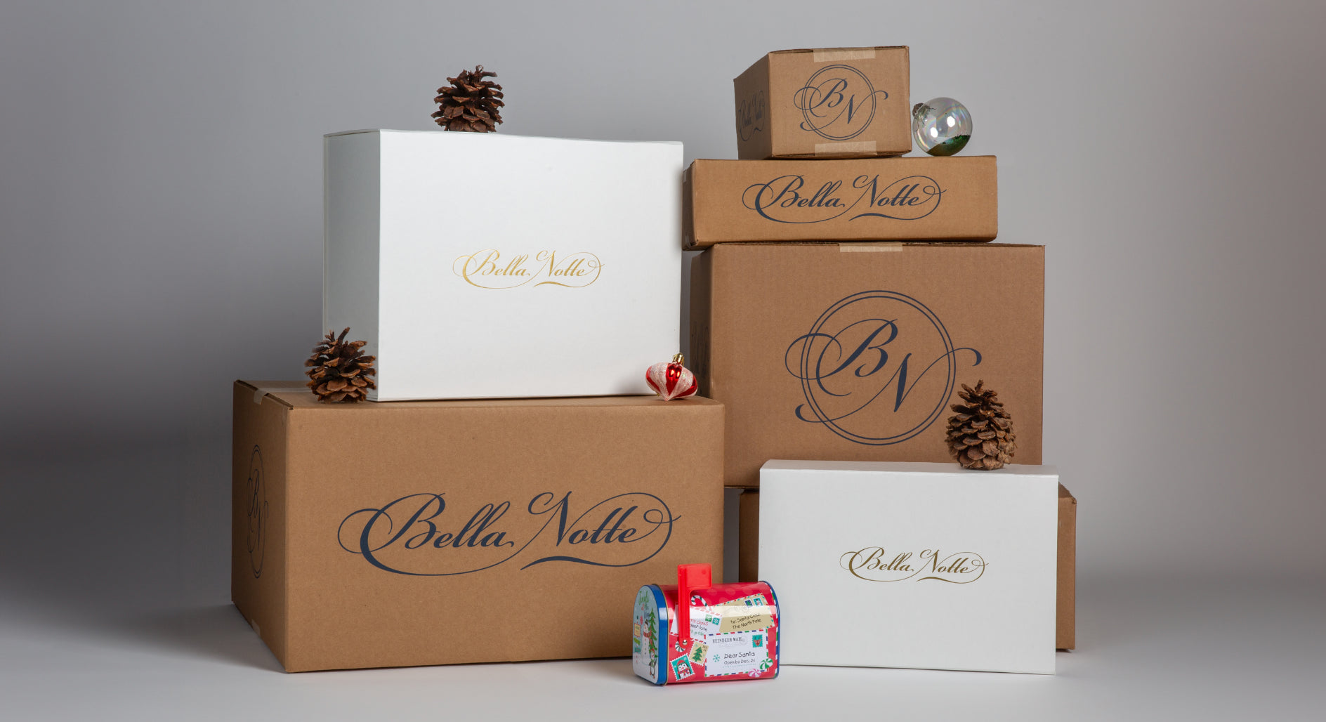 Holiday Resource Guide - brown and white gift boxes branded with the Bella Notte Linens logo are stacked on top of each other and small holiday decorations scattered around