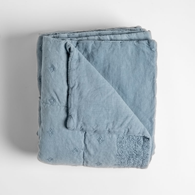 Ines Blanket | Tahoe Blue | Overhead shot of the Ines bedspread folded with a corner showing the inside of the blanket.