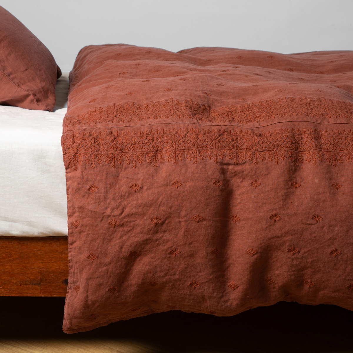 Autumn | A close-up side view of a bed with our Ines Duvet cover and a matching pillowcase in Autumn, a rich terracotta tone.