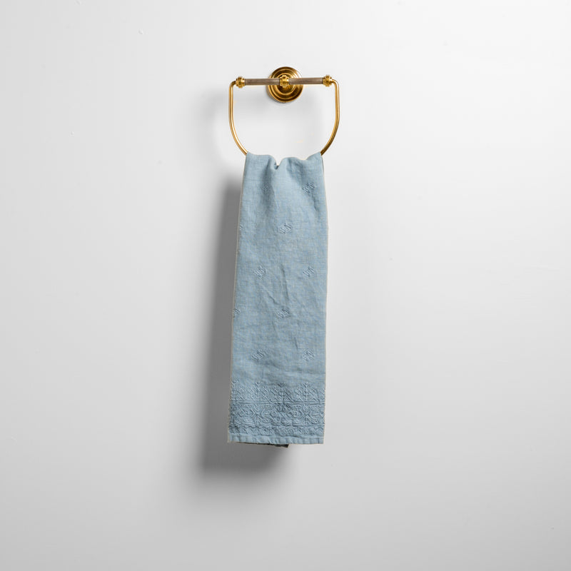 Ines Guest Towel | Tahoe Blue | guest towel draped through a decorative brass towel ring against a white background.