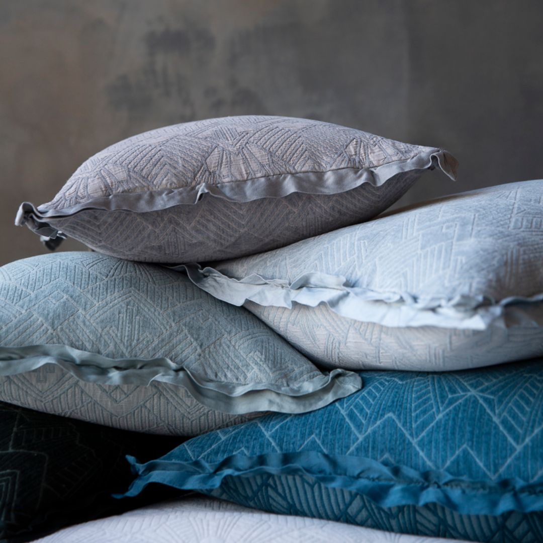A stack of Trettino Throw Pillows in French Lavender, Cloud, Cenote