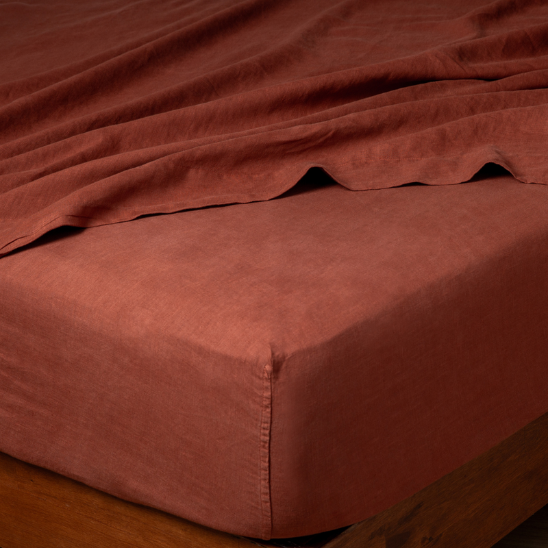 Autumn | A close-up of a bed corner in a Linen fitted sheet in Autumn, a rich terracotta tone.