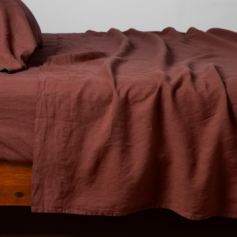 Linen Fitted Sheet | Autumn | A close-up side view of a bed with the Linen flat sheet with the matching sham and pillow in Autumn, a rich terracotta tone.