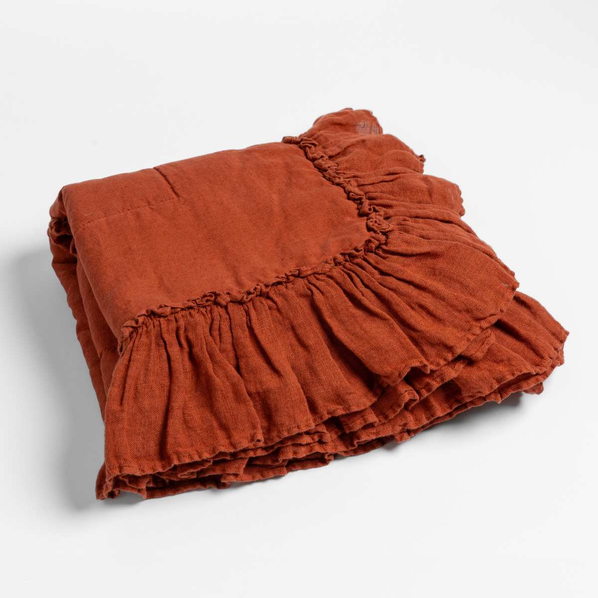 Autumn | A close-up of the corner of a folded Linen Whisper Baby Blanket in Autumn, a rich terracotta tone, shown against a white background.
