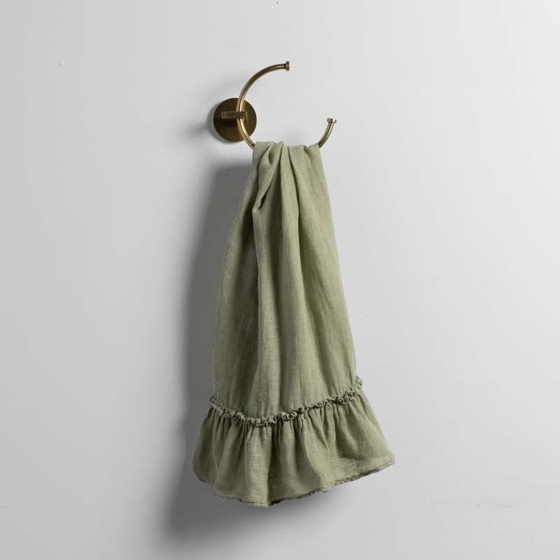 Linen Whisper Guest Towel | Desert Sage | a linen guest towel on a decorative towel ring in desert sage, a serenely elegant green, offering a hushed hue, shown against a plain background.