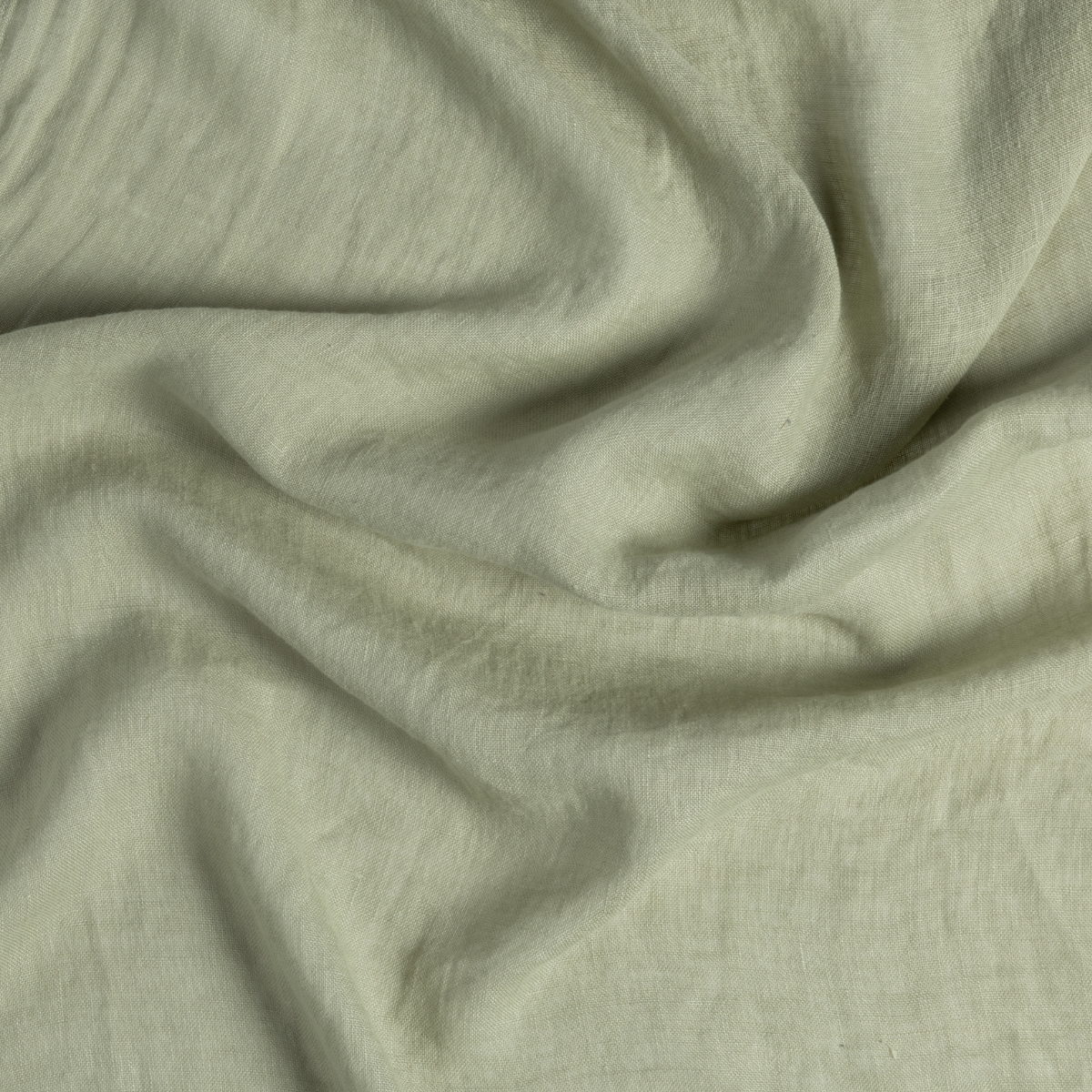 Linen Whisper Bed Skirt | Desert Sage | close-up of whisperweight linen fabric gently rumpled in desert sage, a serenely elegant green, offering a hushed hue.