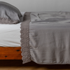 Madera Luxe Pillowcase (Single) | French Lavender | matching tencel pillowcase and flat sheet trimmed with cotton lace on a bed shown from the side view.