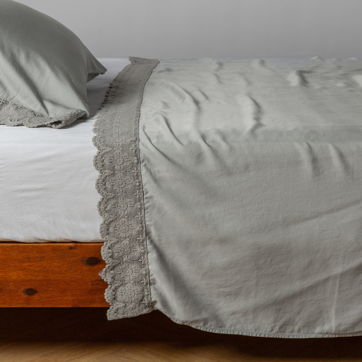 Madera Luxe Flat Sheet | Mineral | matching tencel flat sheet and pillowcase with cotton lace trim on a bed shown from the side