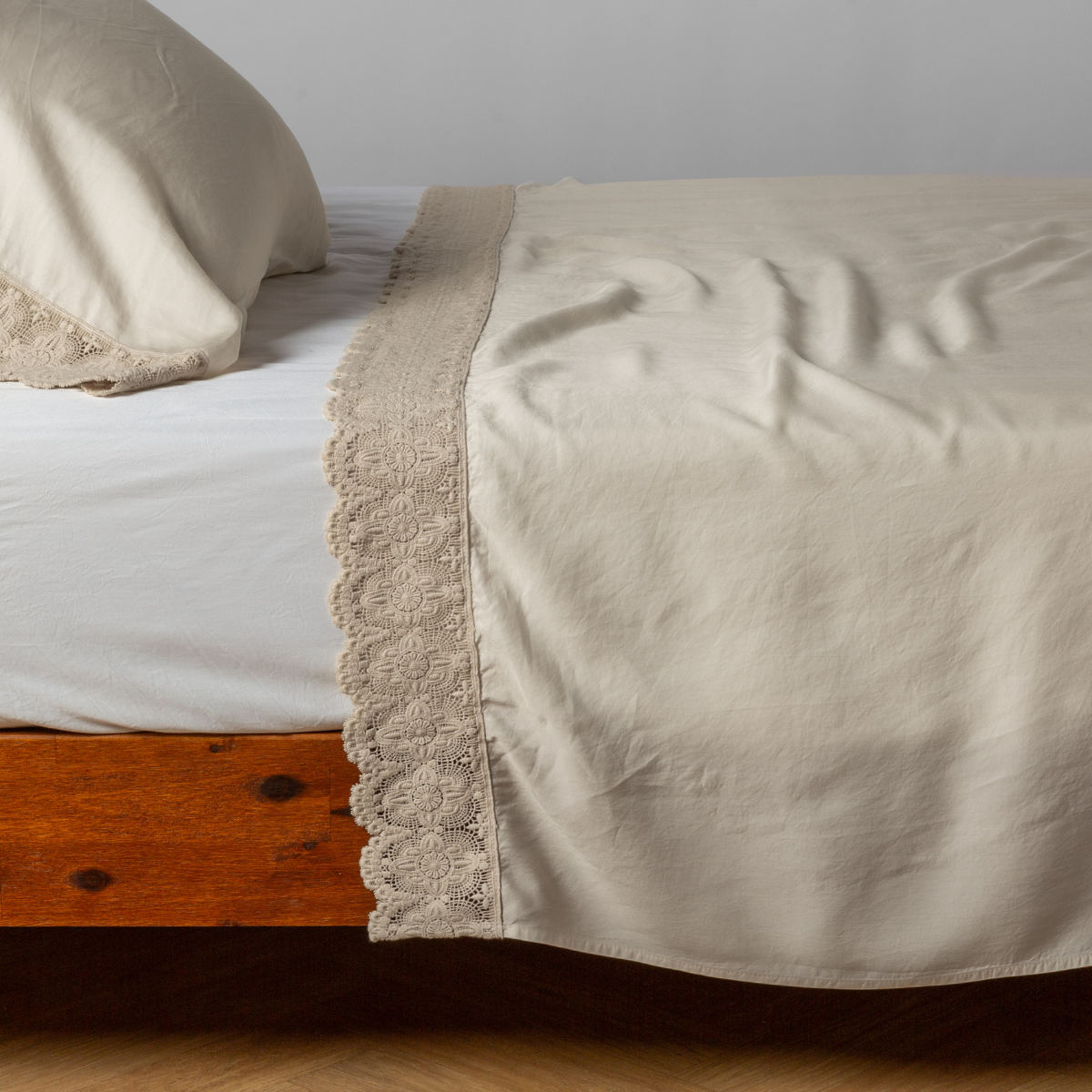 Madera Luxe Flat Sheet | Parchment | matching tencel flat sheet and pillowcase with cotton lace trim on a bed shown from the side