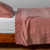 Madera Luxe Pillowcase (Single) | Poppy | matching tencel pillowcase and flat sheet trimmed with cotton lace on a bed shown from the side view.