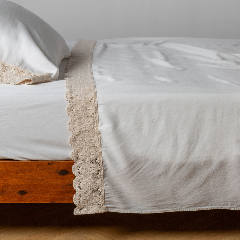 Madera Luxe Flat Sheet | Winter White | matching tencel flat sheet and pillowcase with cotton lace trim on a bed shown from the side
