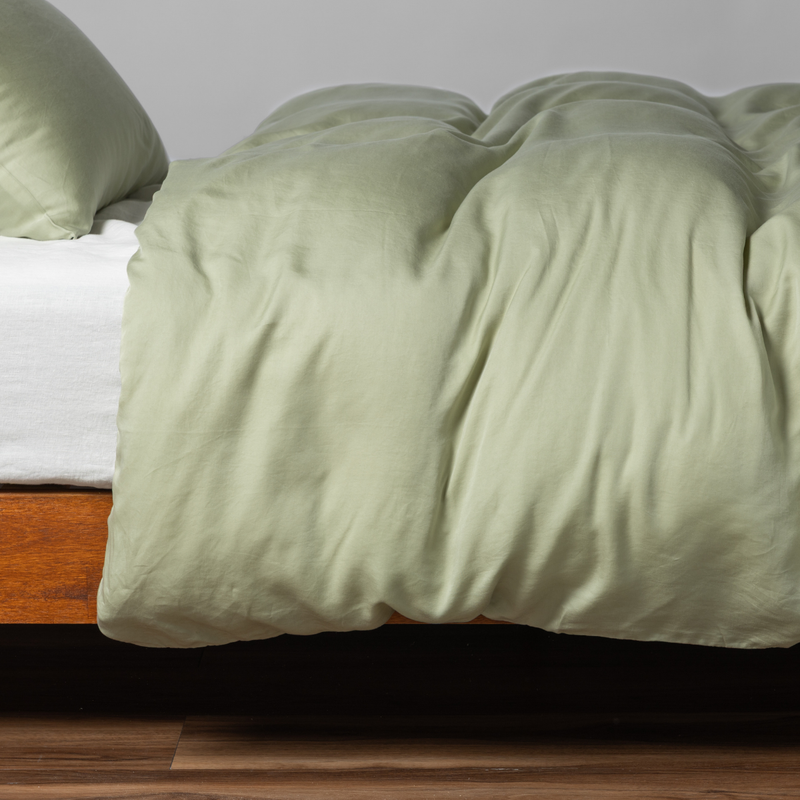 Madera Luxe Duvet Cover | Desert Sage | matching madera luxe and pillowcase in desert sage, a serenely elegant green, offering a hushed hue, shown from the side on a bed against a plain background.