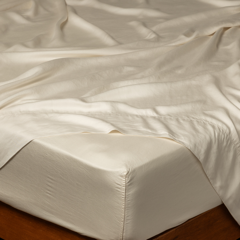 Madera Luxe Fitted Sheet | Natural | close up of corner of a tencel fitted sheet with a gently rumpled flat sheet.