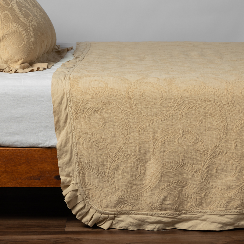 Marisette Bedspread | Honeycomb | matching organic cotton damask trimmed with linen bedspread and sham on a bed with white fitted sheet, shown from the side against a plain background.