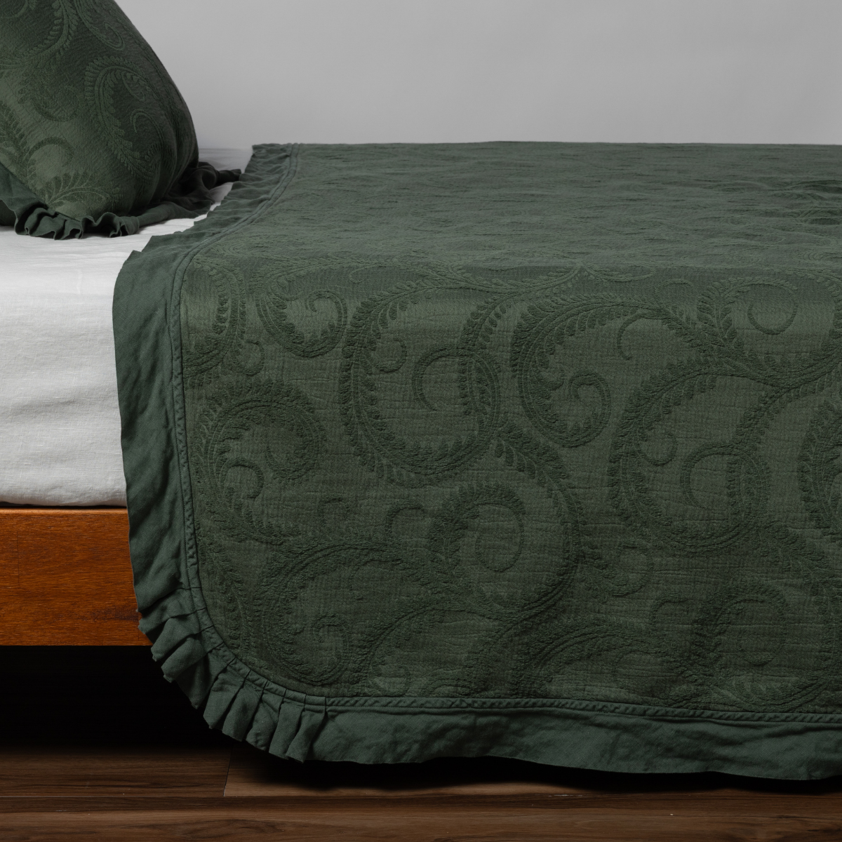 Marisette Bedspread | Juniper | matching organic cotton damask trimmed with linen bedspread and sham on a bed with white fitted sheet, shown from the side against a plain background.