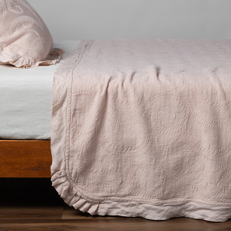 Marisette Bedspread | Pearl | matching organic cotton damask trimmed with linen bedspread and sham on a bed with white fitted sheet, shown from the side against a plain background.