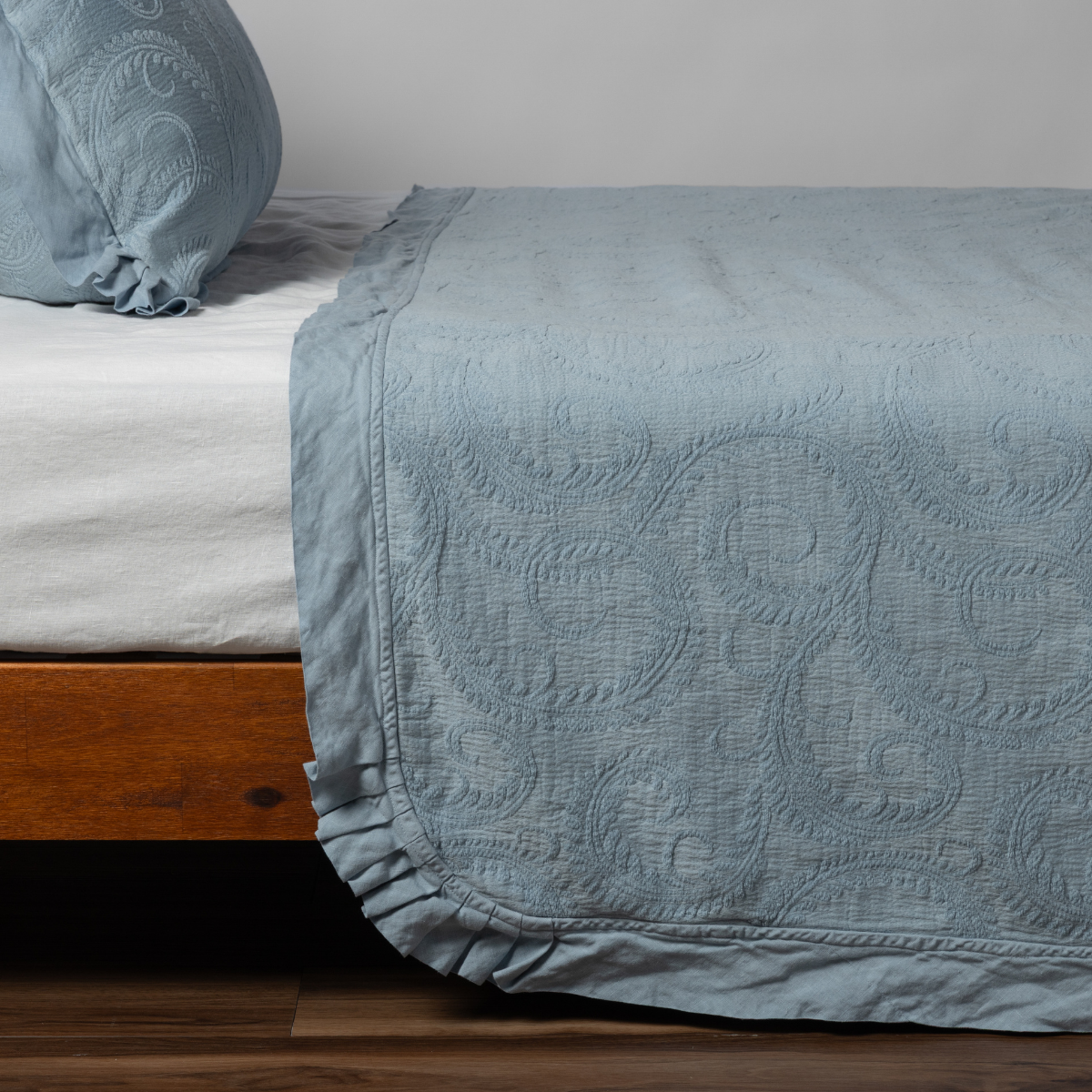 Marisette Bedspread | Tahoe Blue | matching organic cotton damask trimmed with linen bedspread and sham on a bed with white fitted sheet, shown from the side against a plain background.