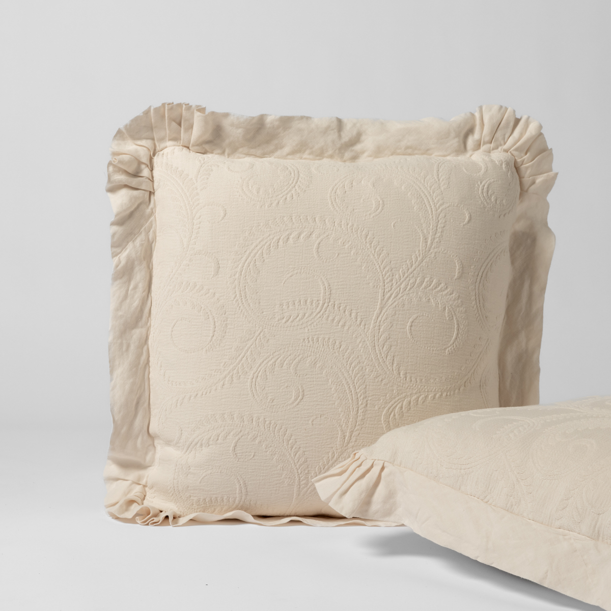 Marisette Sham | Natural | a matching pair of organic cotton damask shams, one upright and one on its side shown against a white background.