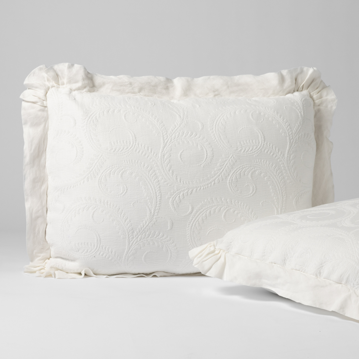 Marisette Sham | Winter White | a matching pair of organic cotton damask shams, one upright and one on its side shown against a white background.