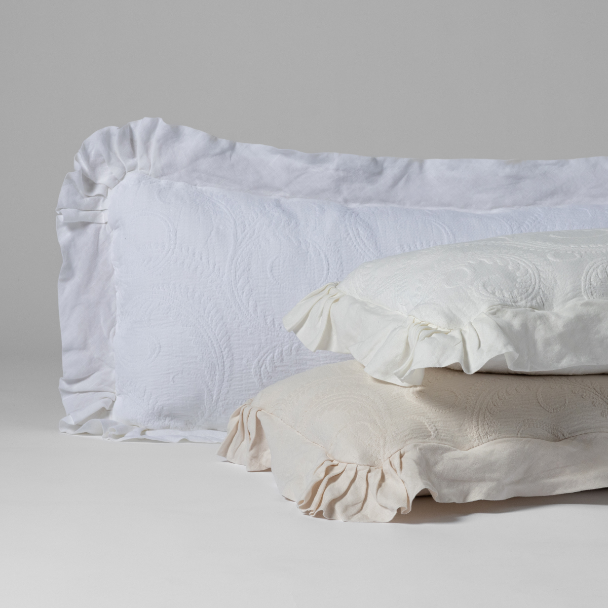Marisette Throw Pillow | organic cotton damask with linen trimmed 16x36-inch throw pillows in White, Winter White and Natural against a plain background.