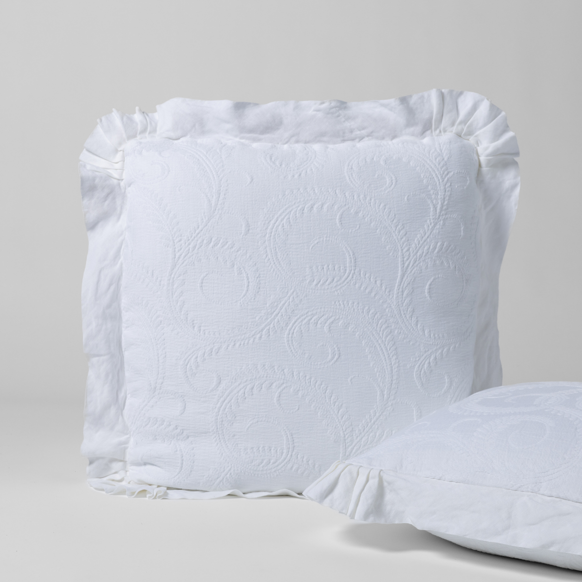 Marisette Sham | White | a matching pair of organic cotton damask shams, one upright and one on its side against a plain background.