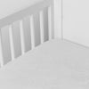 Mirabella Baby Bundle - Holiday Release | Winter White | silk and tencel™ blend jacquard crib sheet shot from above at a slight angle into the corner of a white crib.