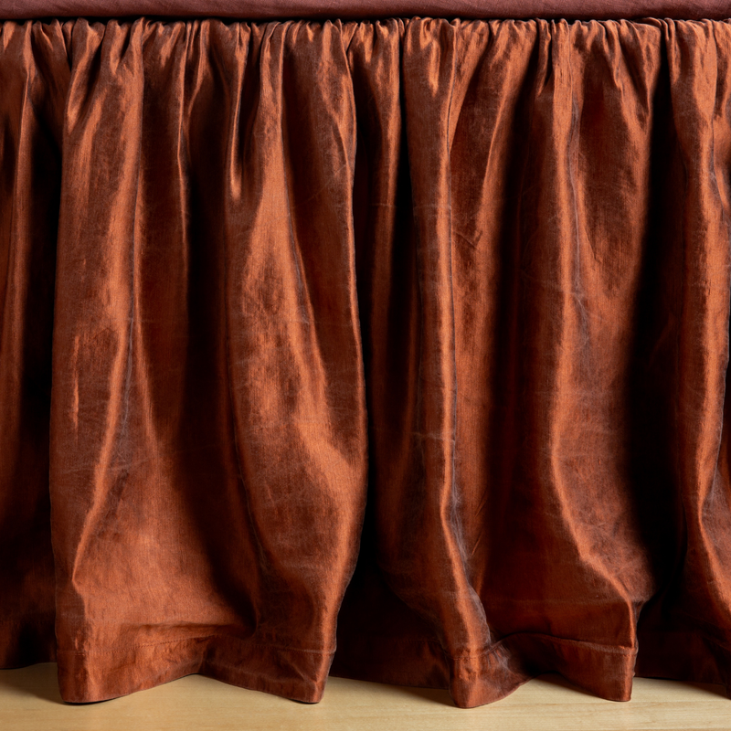 Autumn | A close-up side view of a bed with the Paloma bed skirt in Autumn, a rich terracotta tone.