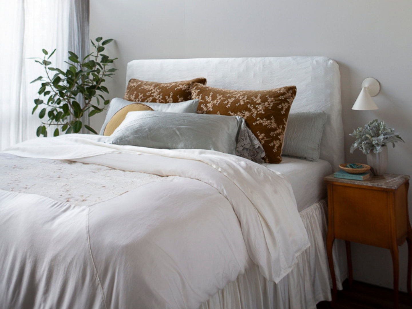 A corner shot of a bed with our signature Lynette Luxe collection front and center in a honeycomb hue against a light-colored bedding ensemble.