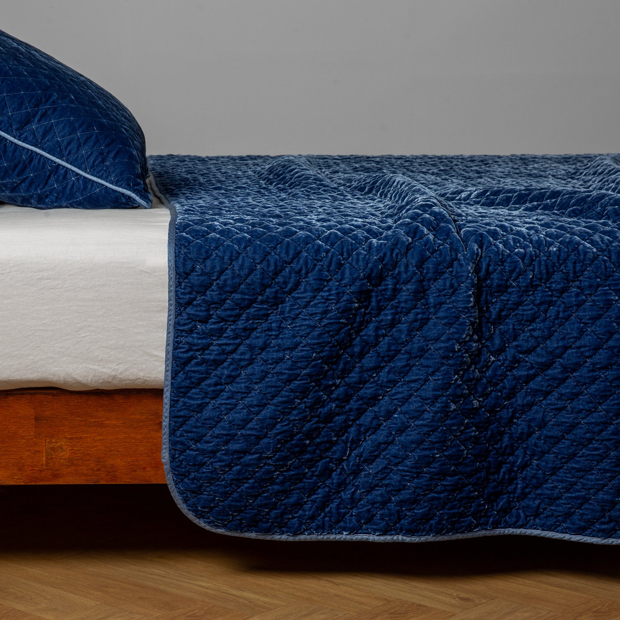 Silk Velvet Quilted Coverlet | Tahoe Blue | A side view of a Tahoe Blue throw blanket with matching sham; Tahoe Blue is a saturated blue like a crystal clear sky.