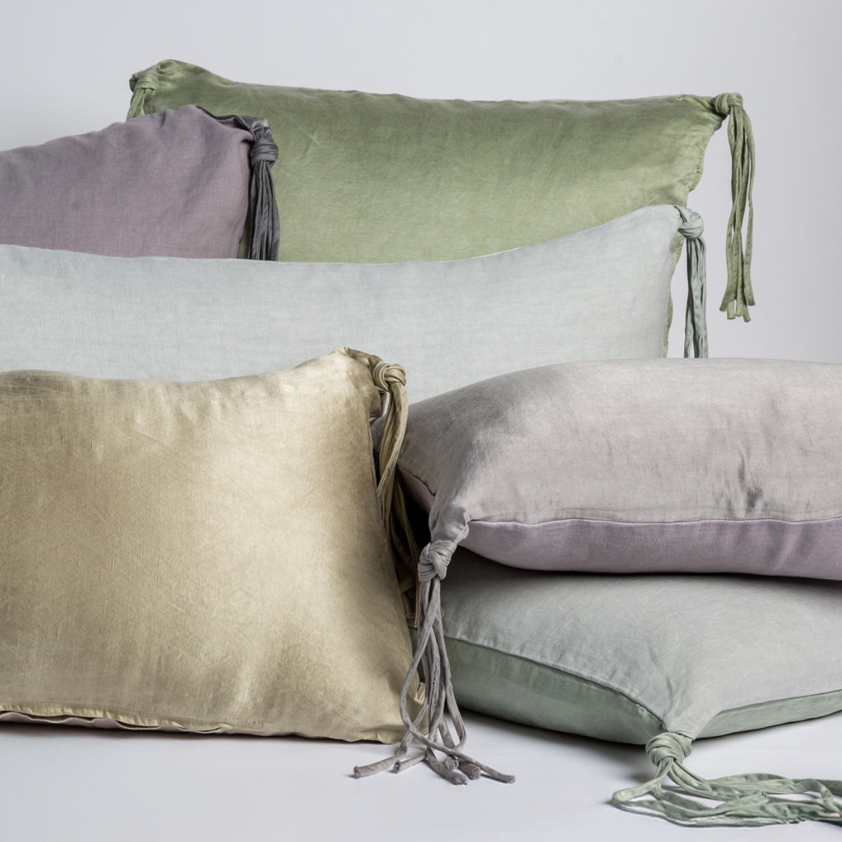 Taline Throw Pillow | charmeuse throw pllows with tassels shown in several sizes and colors againt a white background. 