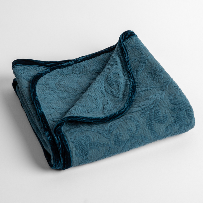 Adele Baby Blanket | Cenote | a folded blanket with the corner turned down to show the trim against a white background, shot from an overhead angle.