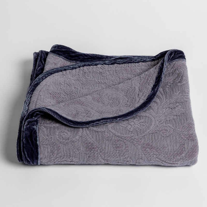 Adele Baby Blanket | French Lavender | a folded blanket with the corner turned down to show the trim against a white background, shot from an overhead angle.
