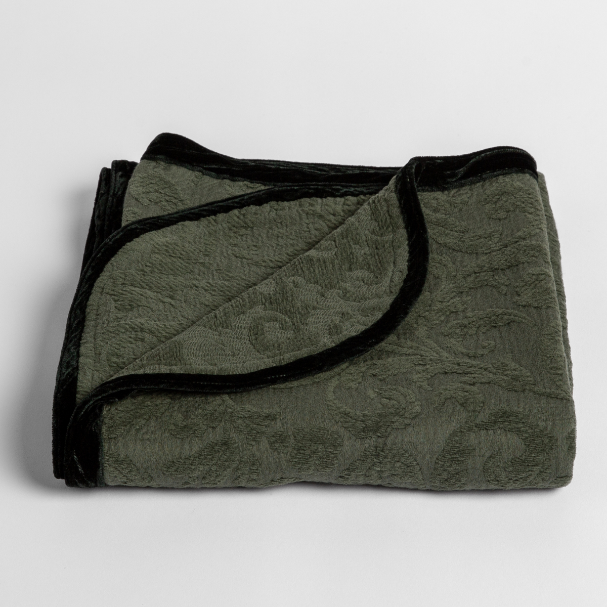 Adele Baby Blanket | Juniper | a folded blanket with the corner turned down to show the trim against a white background, shot from an overhead angle.