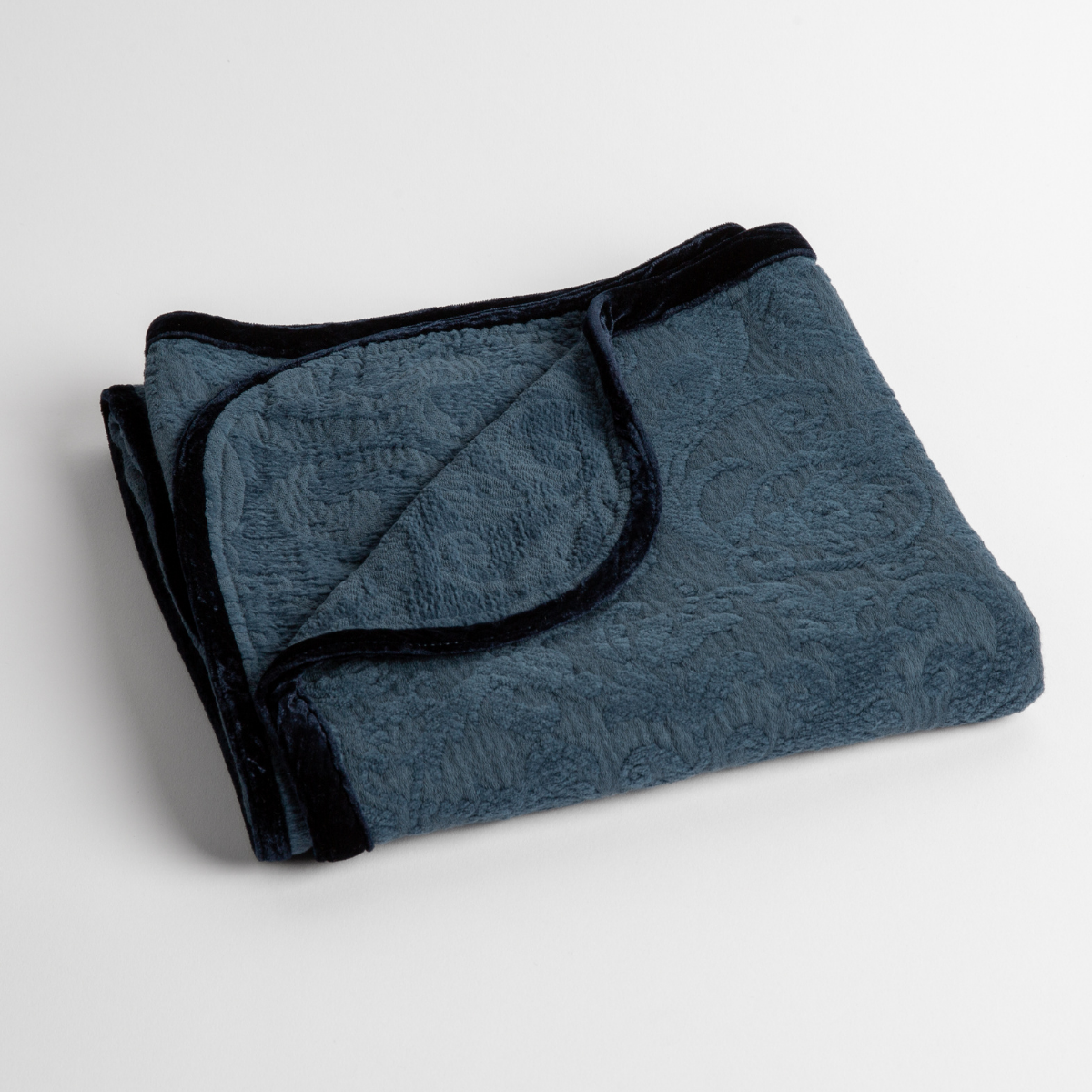 Adele Baby Blanket | Midnight | a folded blanket with the corner turned down to show the trim against a white background, shot from an overhead angle.