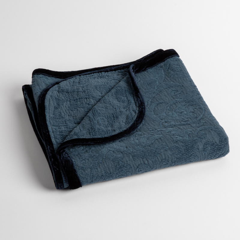 Adele Baby Blanket | Midnight | a folded blanket with the corner turned down to show the trim against a white background, shot from an overhead angle.