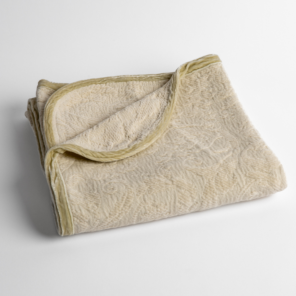 Adele Baby Blanket | Parchment | a folded blanket with the corner turned down to show the trim against a white background, shot from an overhead angle.