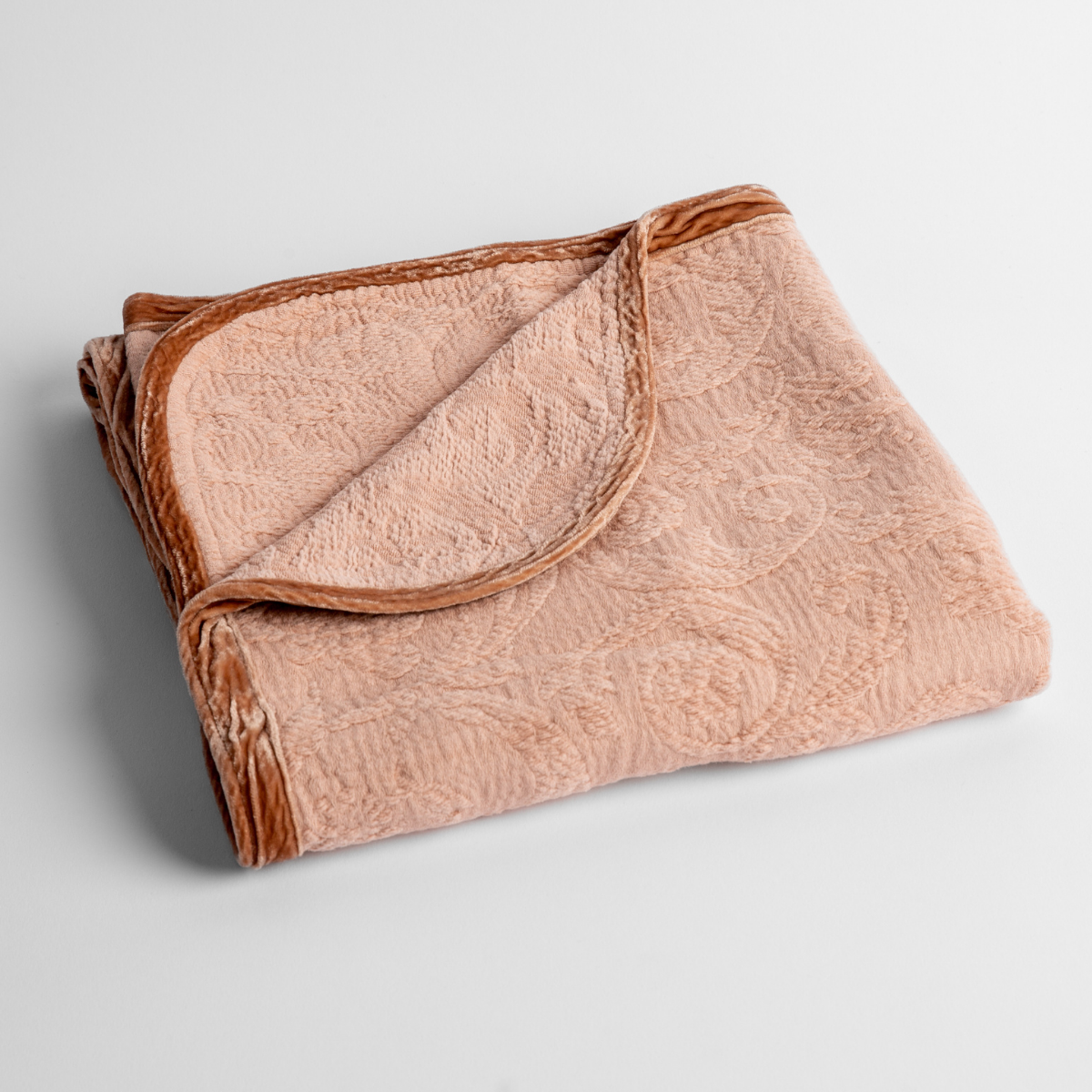 Adele Baby Blanket | Rouge | a folded blanket with the corner turned down to show the trim against a white background, shot from an overhead angle.
