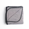 Adele Blanket | Fog | folded organic cotton damask throw blanket shown with the corner folded down to show silk velvet trim detail — overhead against a plain white background.