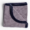 Adele Blanket | French Lavender | folded organic cotton damask throw blanket shown with the corner folded down to show silk velvet trim detail — overhead against a plain white background.