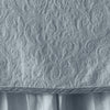 Cloud | Close up of the Adele coverlet in cloud, highlighting the detail of the cotton damask and the silk velvet edging trim. A white bed skirt peeks out at the bottom of the shot.