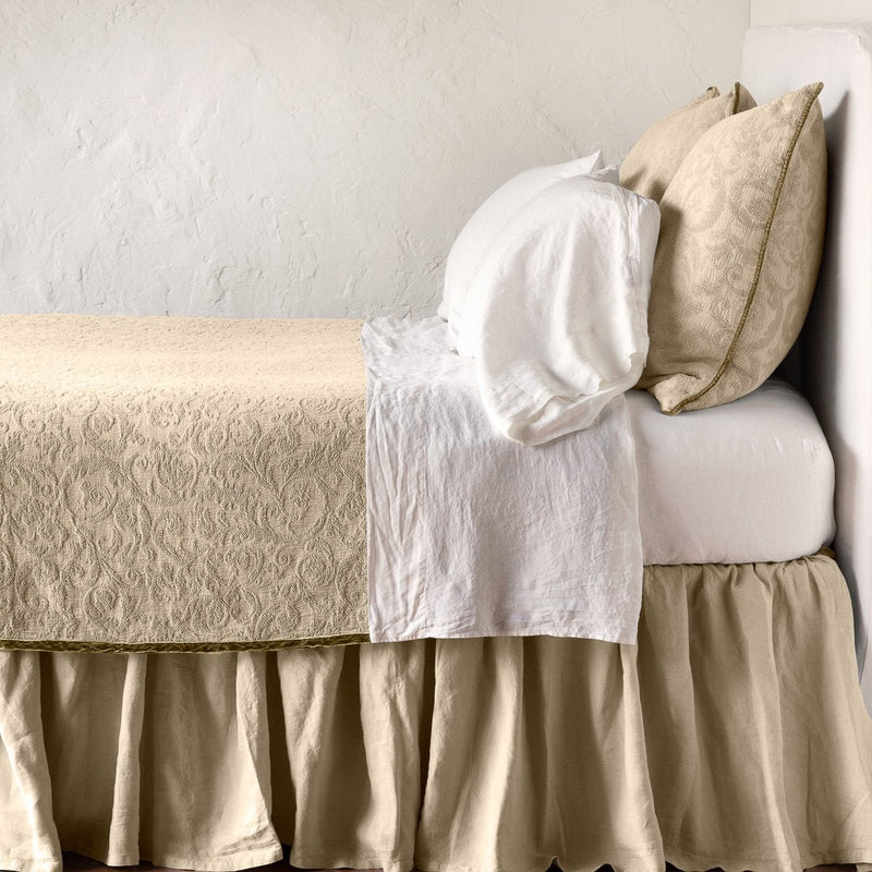 Honeycomb | The Adele coverlet in honeycomb, on a bed viewed from the side against a plain white wall. The bed is styled neatly with the coverlet folded back to reveal white sheets, bed skirt and pillows.