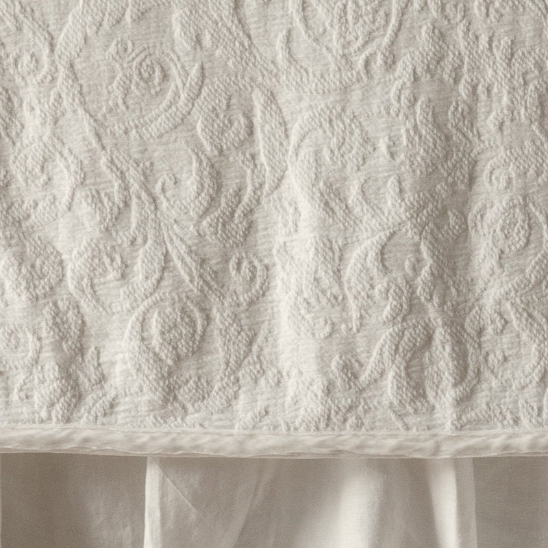 Parchment | Close up of the Adele coverlet in parchment, highlighting the detail of the cotton damask and the silk velvet edging trim. A parchment bed skirt peeks out at the bottom of the shot.