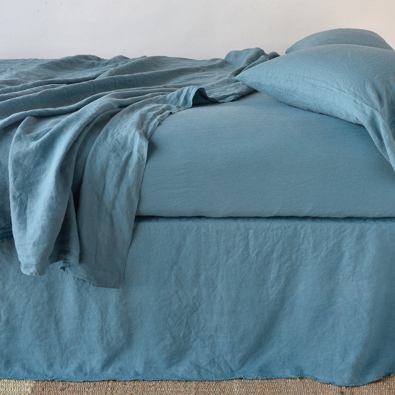 Cenote | Austin bed skirt in cenote shown from the side on a bed with monochromatic sheeting, highlighting its tailored, ungathered style.