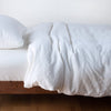 Austin Duvet Cover | White | Midweight linen duvet cover in white on a bed, side view.