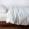 Austin Duvet Cover | Winter White | Midweight linen duvet cover in winter white on a bed, side view.