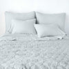 Austin Coverlet | Cloud | Quilted midweight linen coverlet in cloud, end of bed view, with monochromatic sheeting and shams.