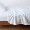 Austin Coverlet | White | Quilted midweight linen coverlet in white on a bed - side view.